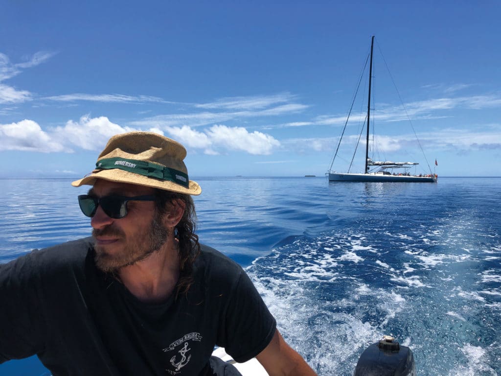 A sailor motoring away from a sailboat.