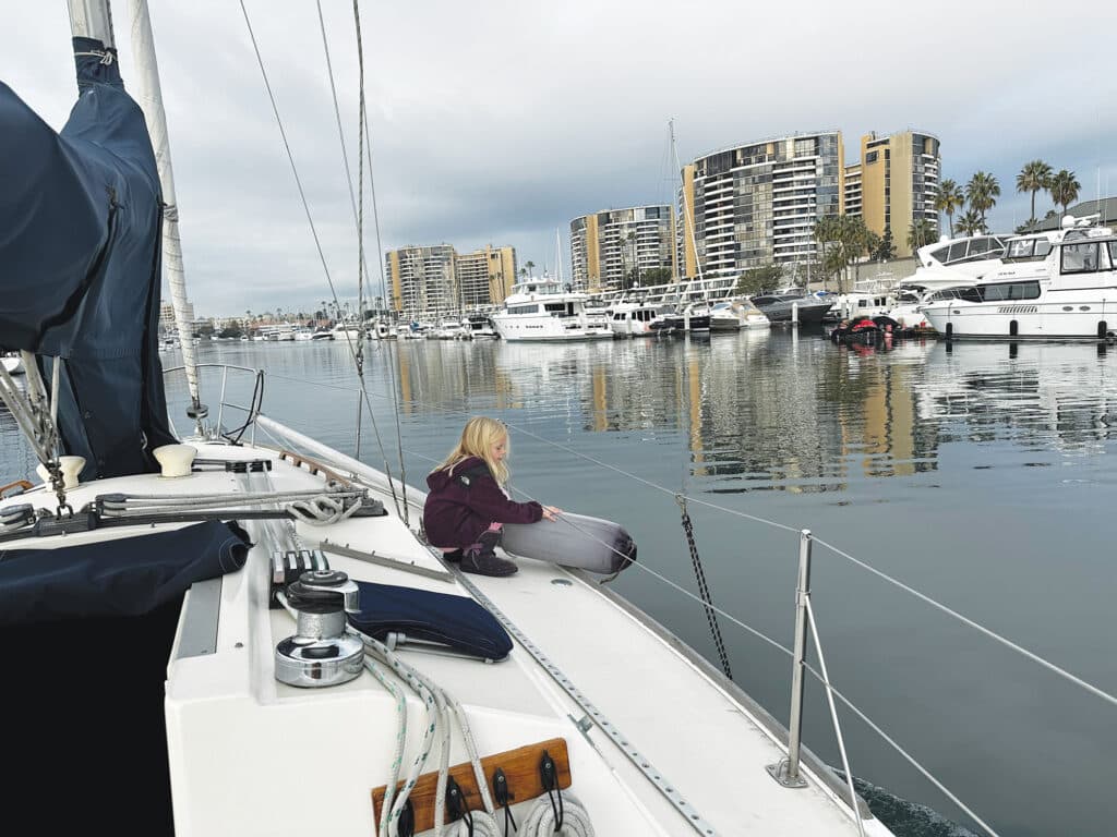 Girl pulling up boat fenders when clearing the dock